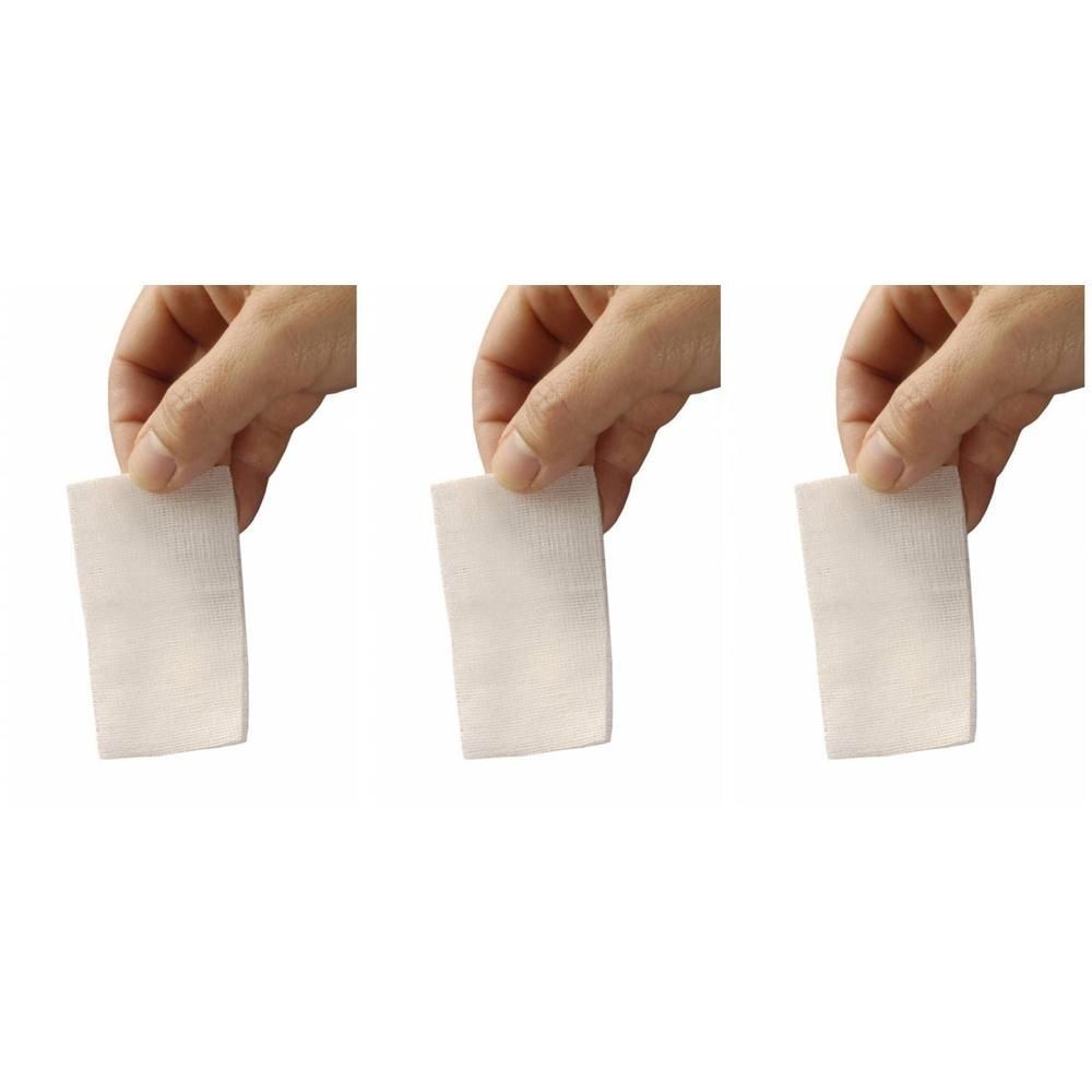 Trois compresses de gaze blanche tenues par des doigts.