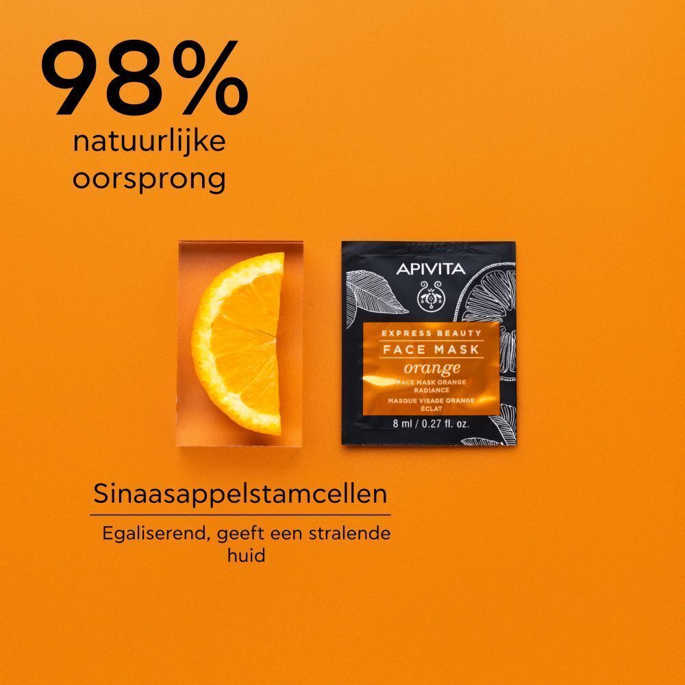 Eén verpakking Apivita Express Beauty Gezichtsmasker Sinaasappel naast sinaasappelschijf.