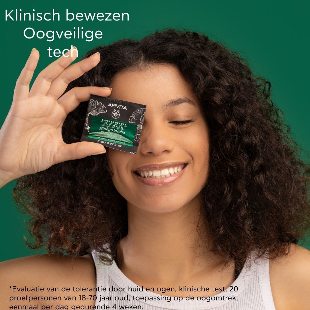 Vrouw houdt Apivita Express Beauty oogmasker voor haar oog.