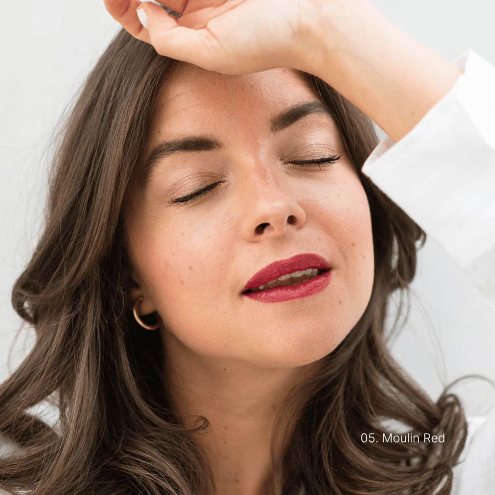 Vrouw met gesloten ogen draagt rode lippenstift, kleur 05 Moulin Red.