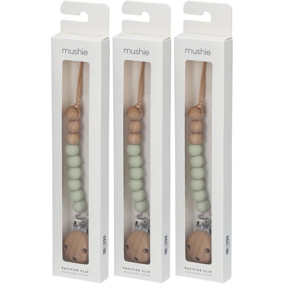 Trois attaches-sucette Mushie avec perles en bois et silicone vert sauge, en emballage blanc.