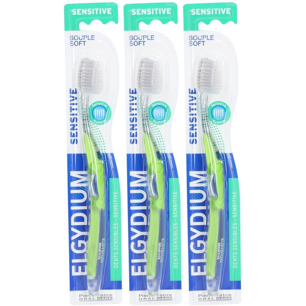 Drie Elgydium Sensitive tandenborstels met zachte borstels en groene handvatten, verpakt.