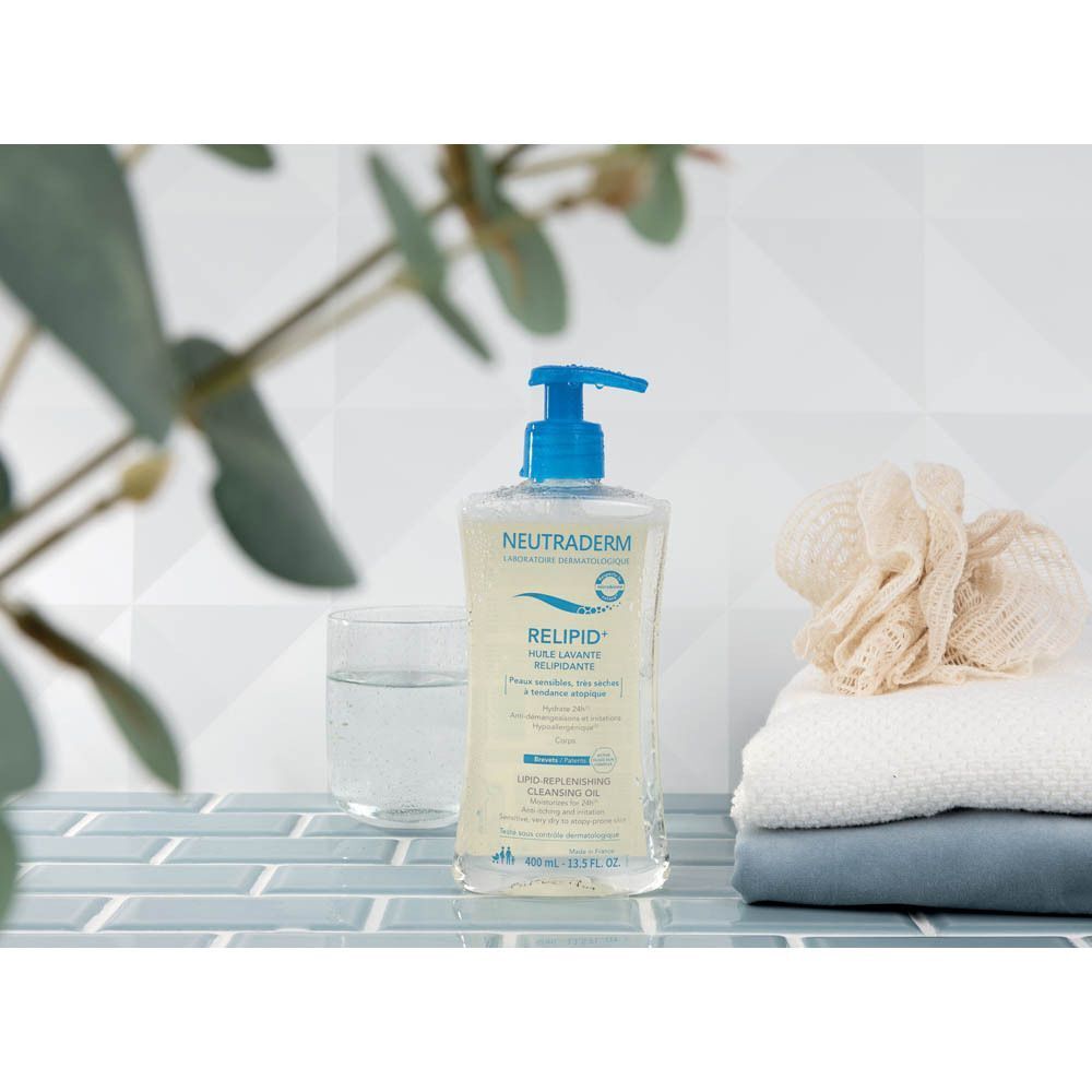 Flacon de Neutraderm Relipid+ Huile Lavante Relipidante à côté de serviettes et d'un verre d'eau.