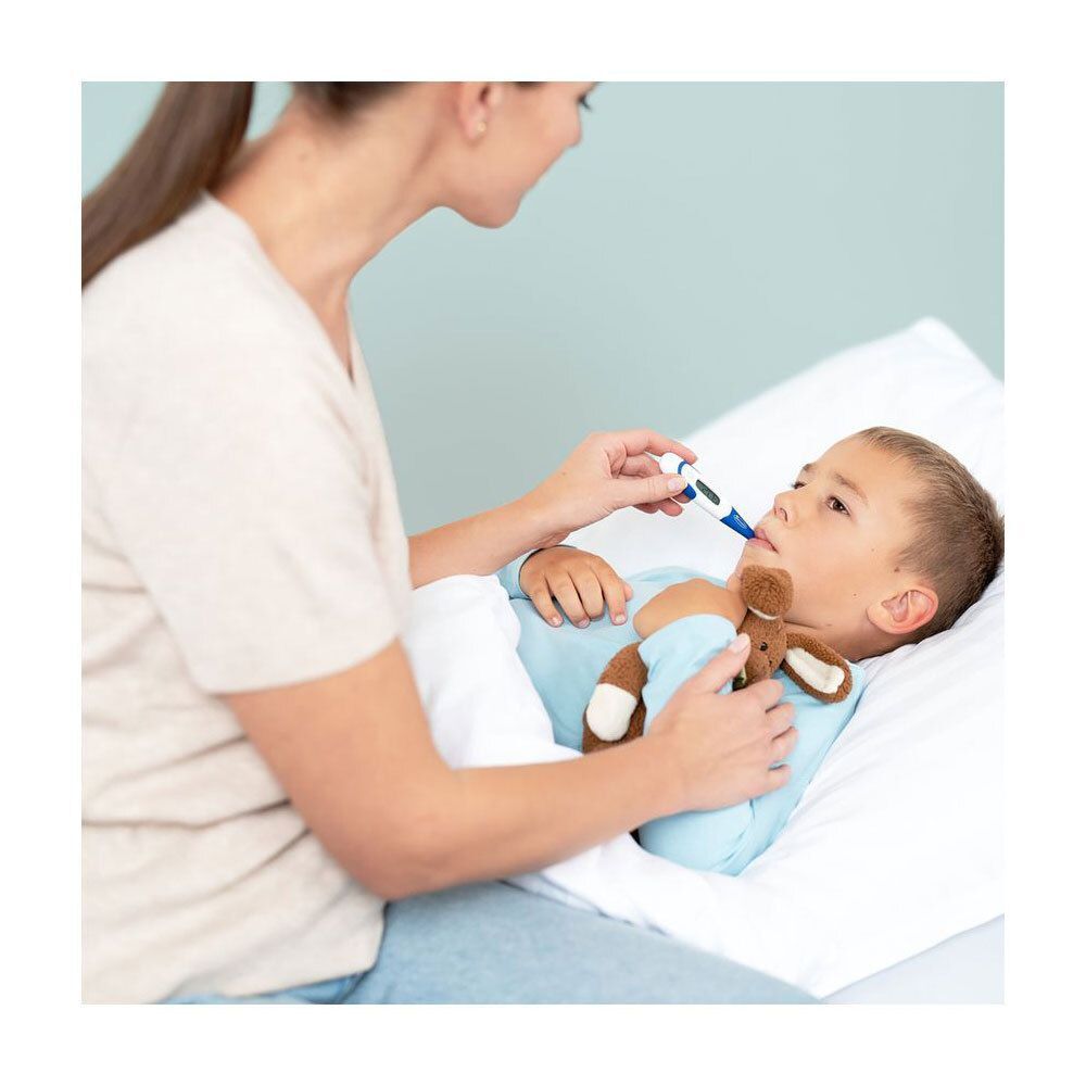 Moeder meet temperatuur bij een jongen in bed met een Hartmann Thermoval® Flex digitale thermometer.
