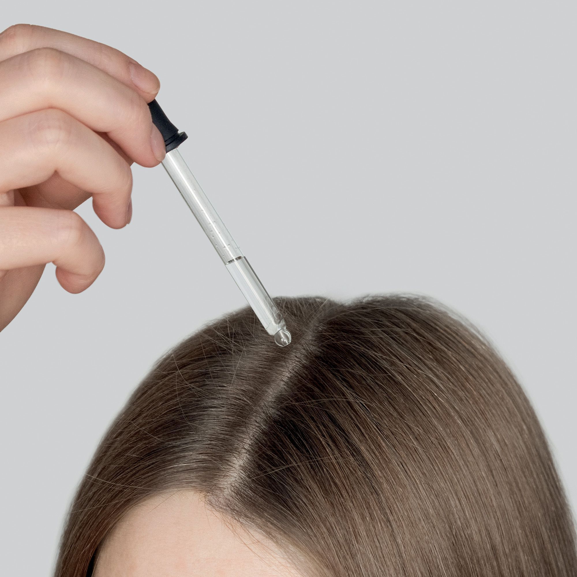 Druppelaar brengt Phyto Polleine Scalp Solution aan op de hoofdhuid scheiding.
