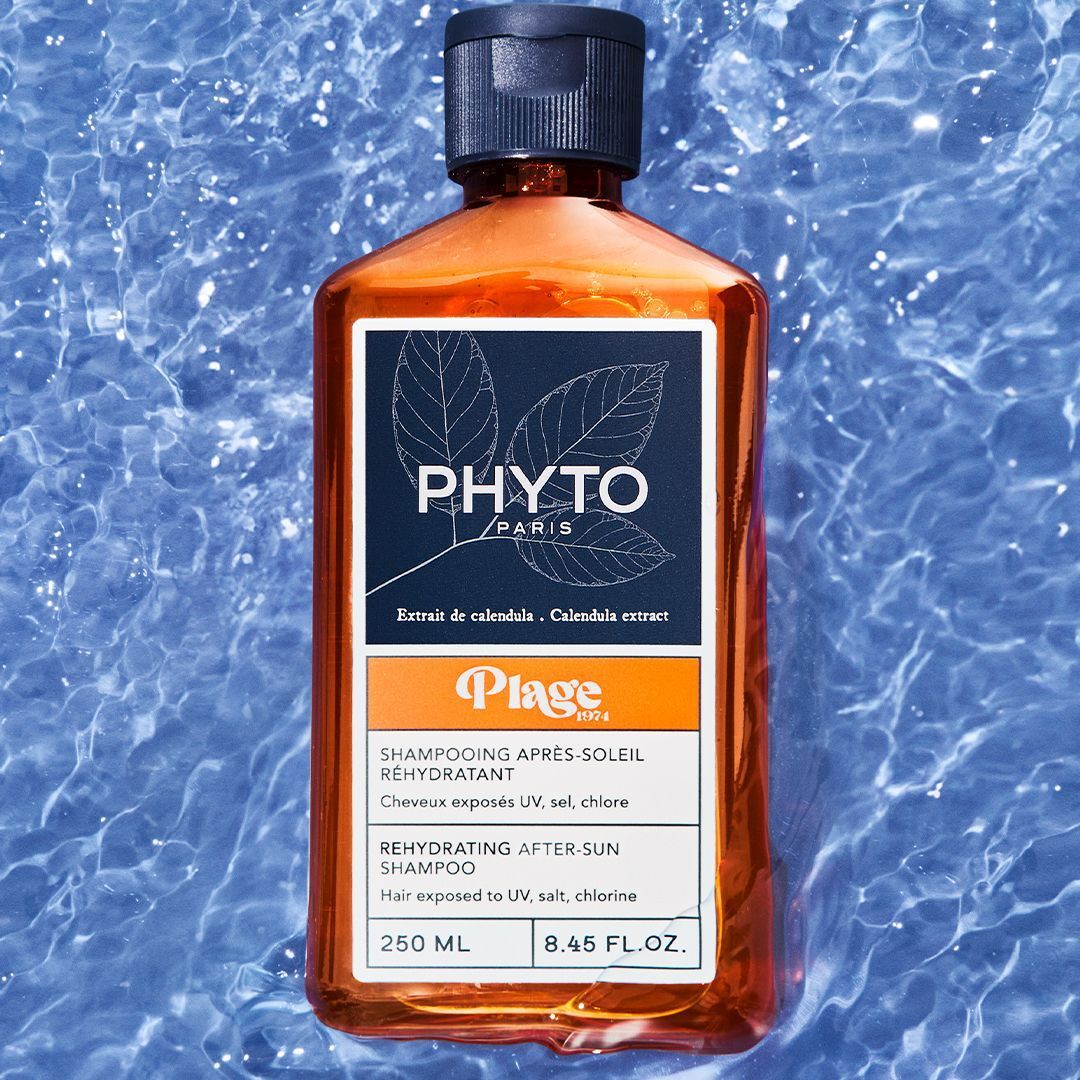Een fles Phyto Plage Shampooing Réhydratant Après-Soleil in het water.
