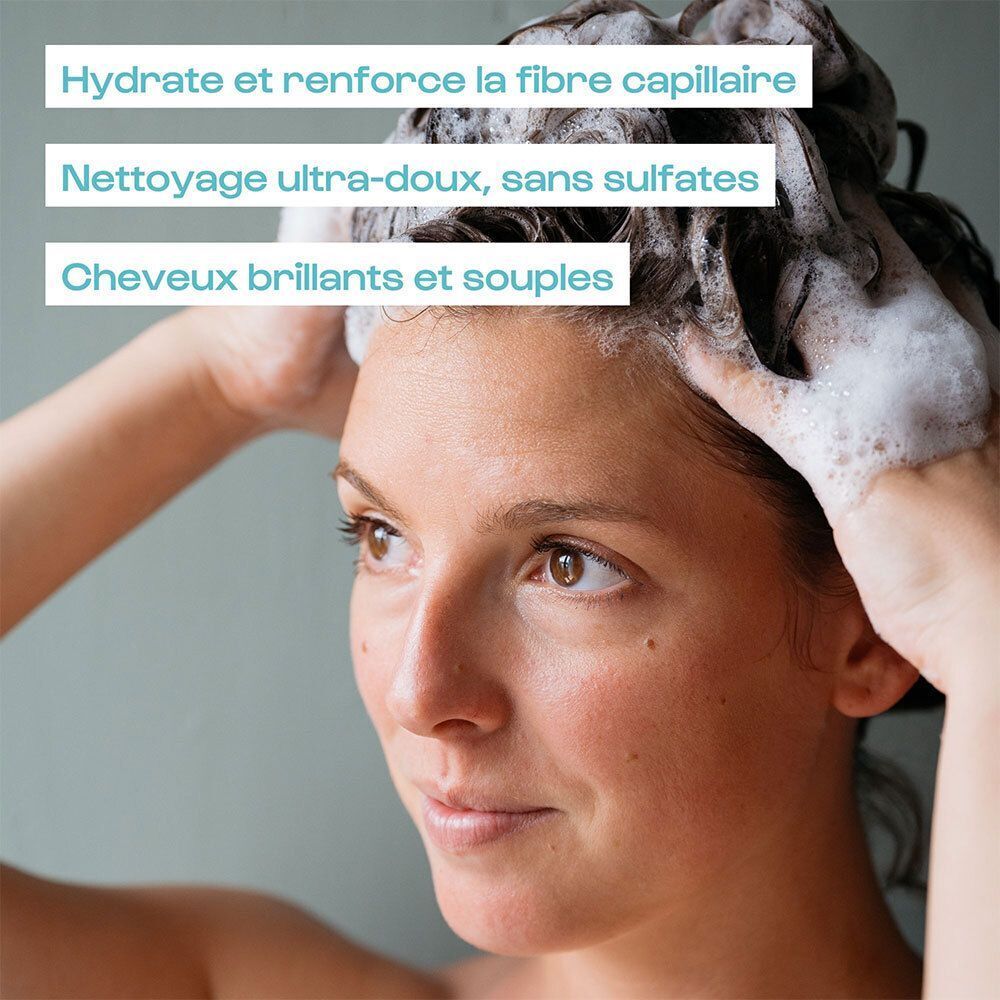 Une femme se lave les cheveux avec du shampoing moussant.