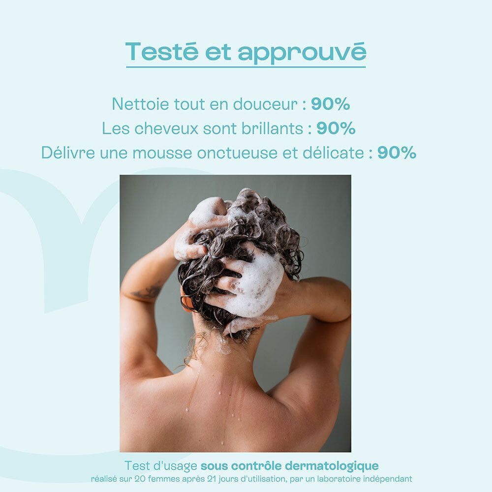 Vue arrière d'une femme se lavant les cheveux avec du shampoing moussant.