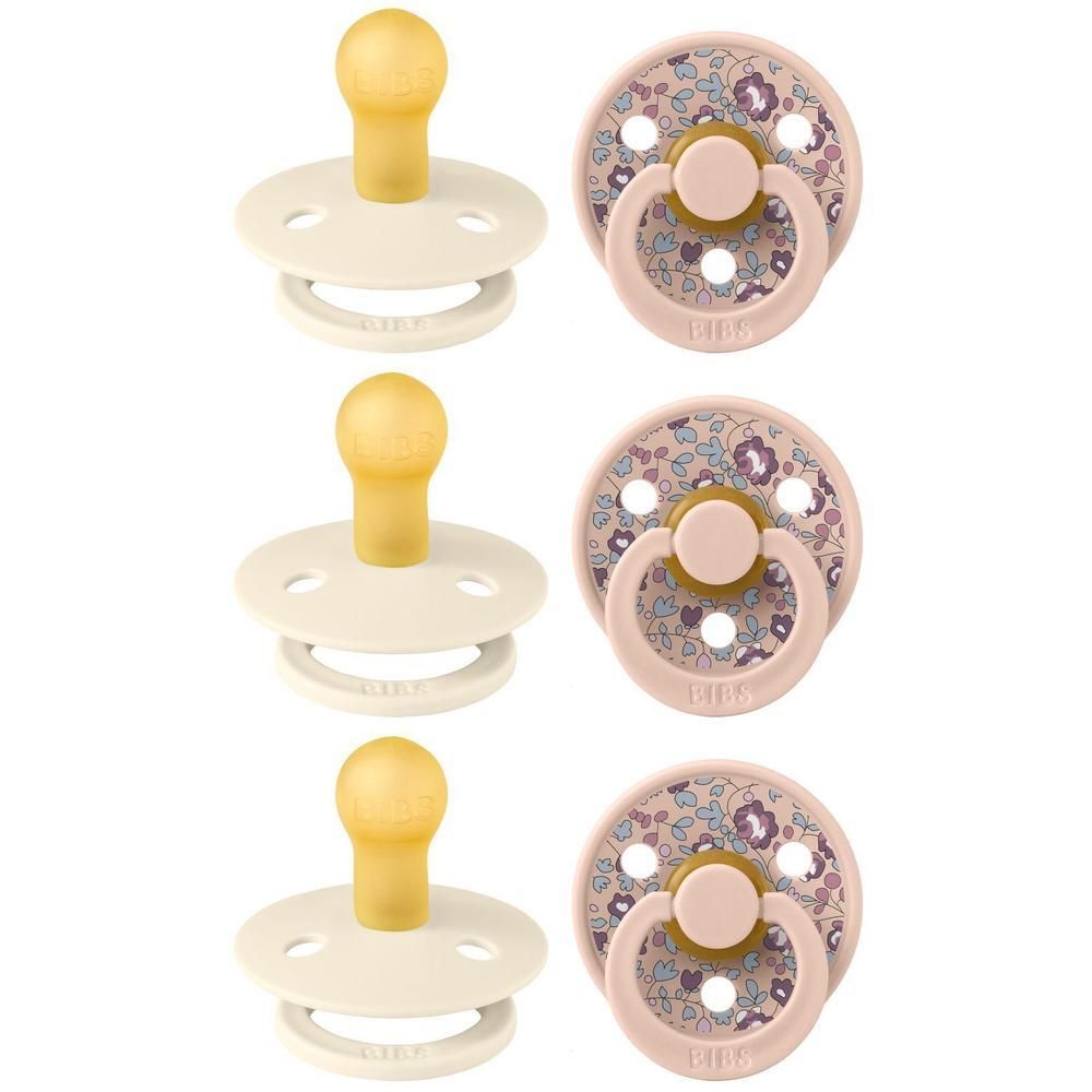 Deux tétines BIBS : une crème avec tétine jaune et une rose à motif floral.