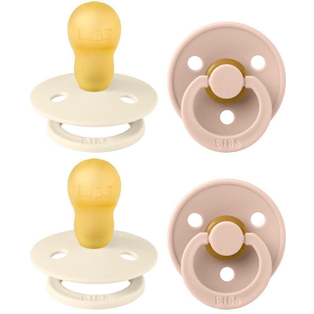 Deux suces BIBS : une couleur ivoire avec tétine jaune, une couleur blush avec poignée dorée.