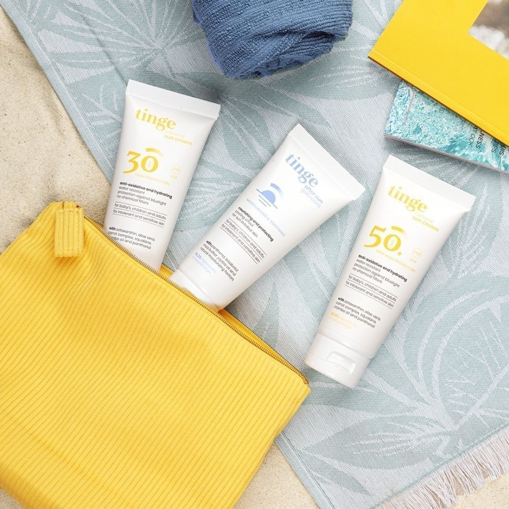 Trois tubes Tinge Gel-Crème Après-Soleil avec des crèmes solaires dans une pochette.