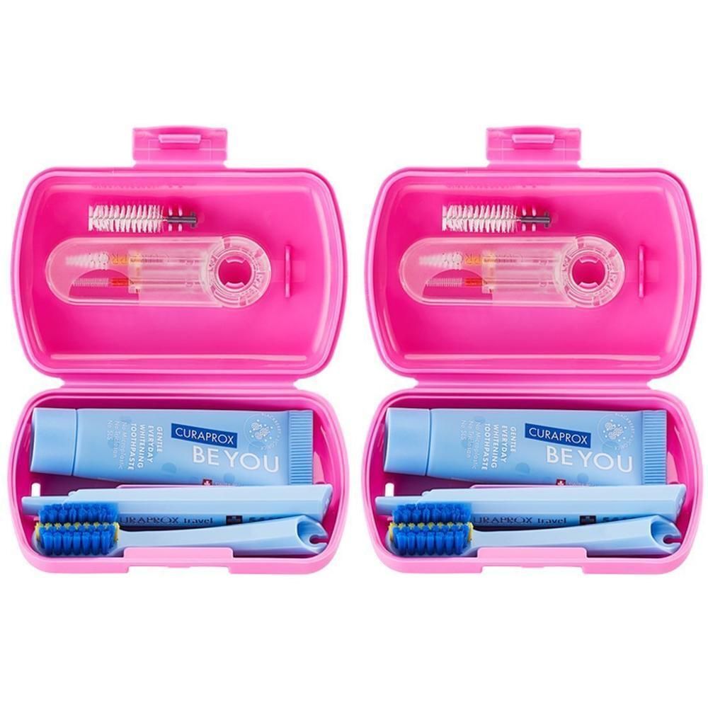 Deux trousses de voyage roses ouvertes contenant des brosses à dents, des brossettes interdentaires et du dentifrice.
