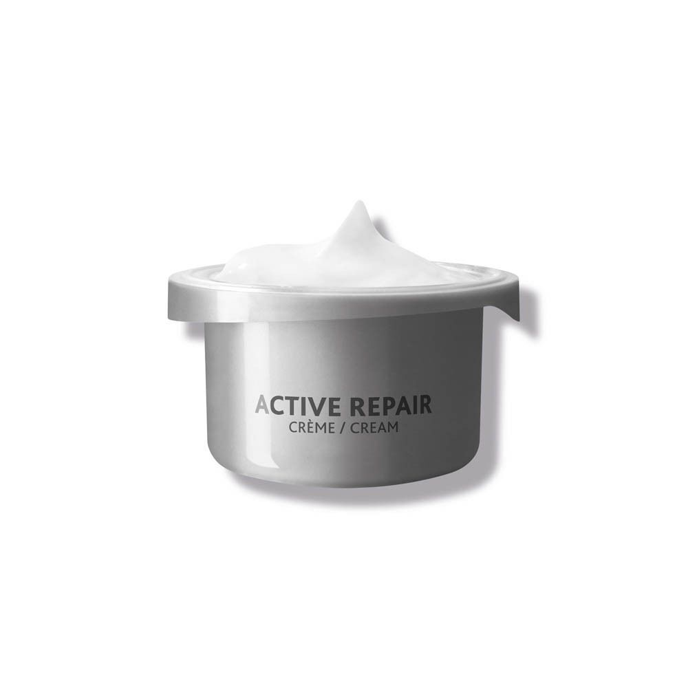 Een potje met opschrift "ACTIVE REPAIR CRÈME / CREAM", gevuld met witte crème.