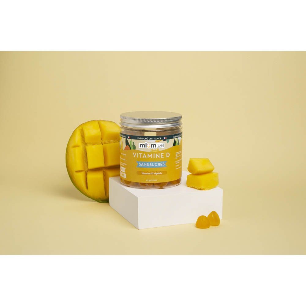Pot de MiumLab Vitamine D gummies à côté de morceaux de mangue et d'une demi-mangue.