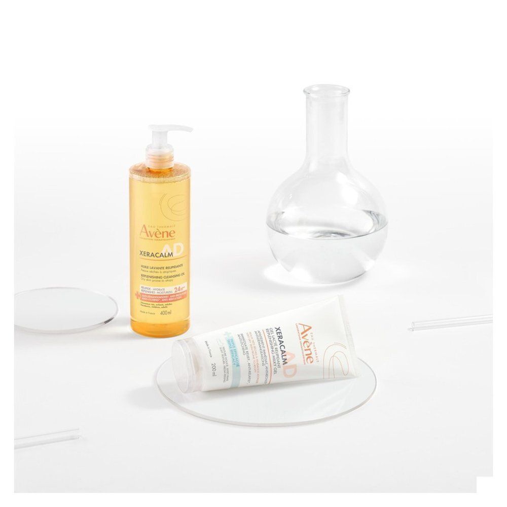 Avène XeraCalm AD Gel-Lait en een fles met dispenser, naast laboratoriumapparatuur.