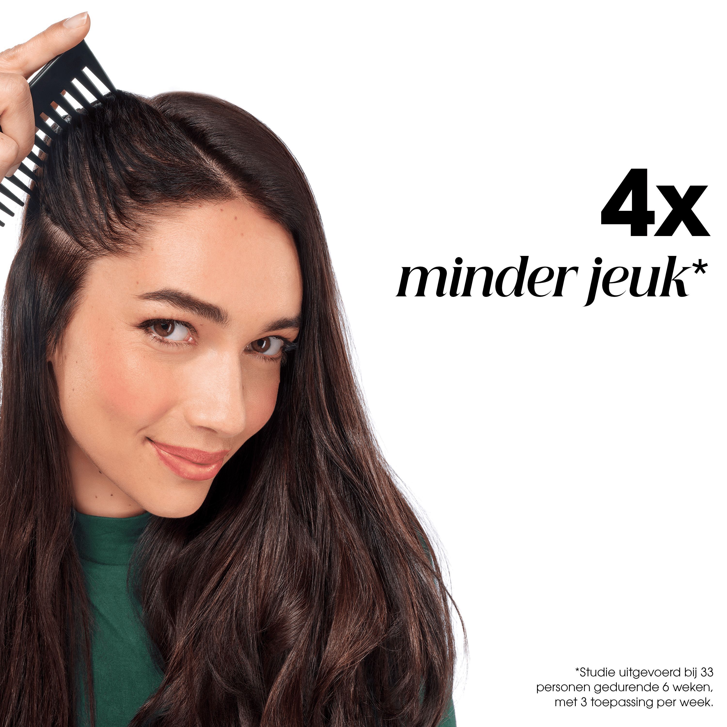Vrouw kamt haar haar, Klorane Anti-Roos Behandeling vermindert jeuk 4x.