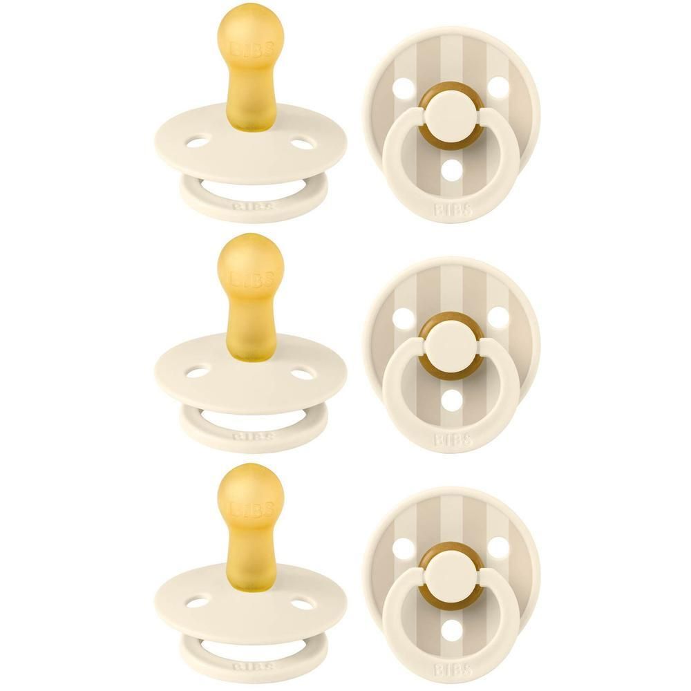 Deux sucettes BIBS couleur crème avec tétine jaune et bouclier rayé blanc et or.