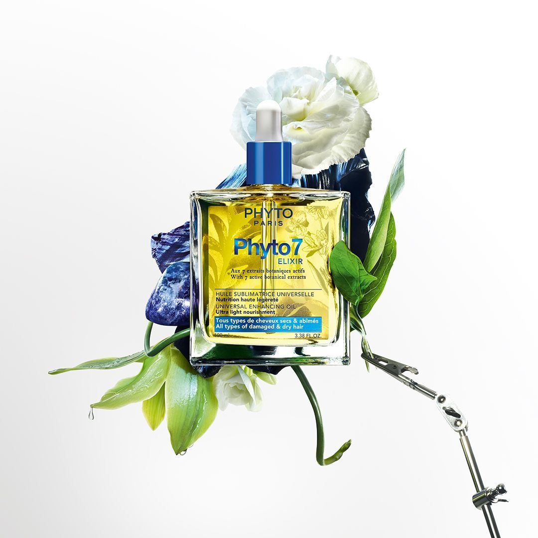 Fles Phyto Paris Phyto7 Elixir omringd door bloemen en bladeren.