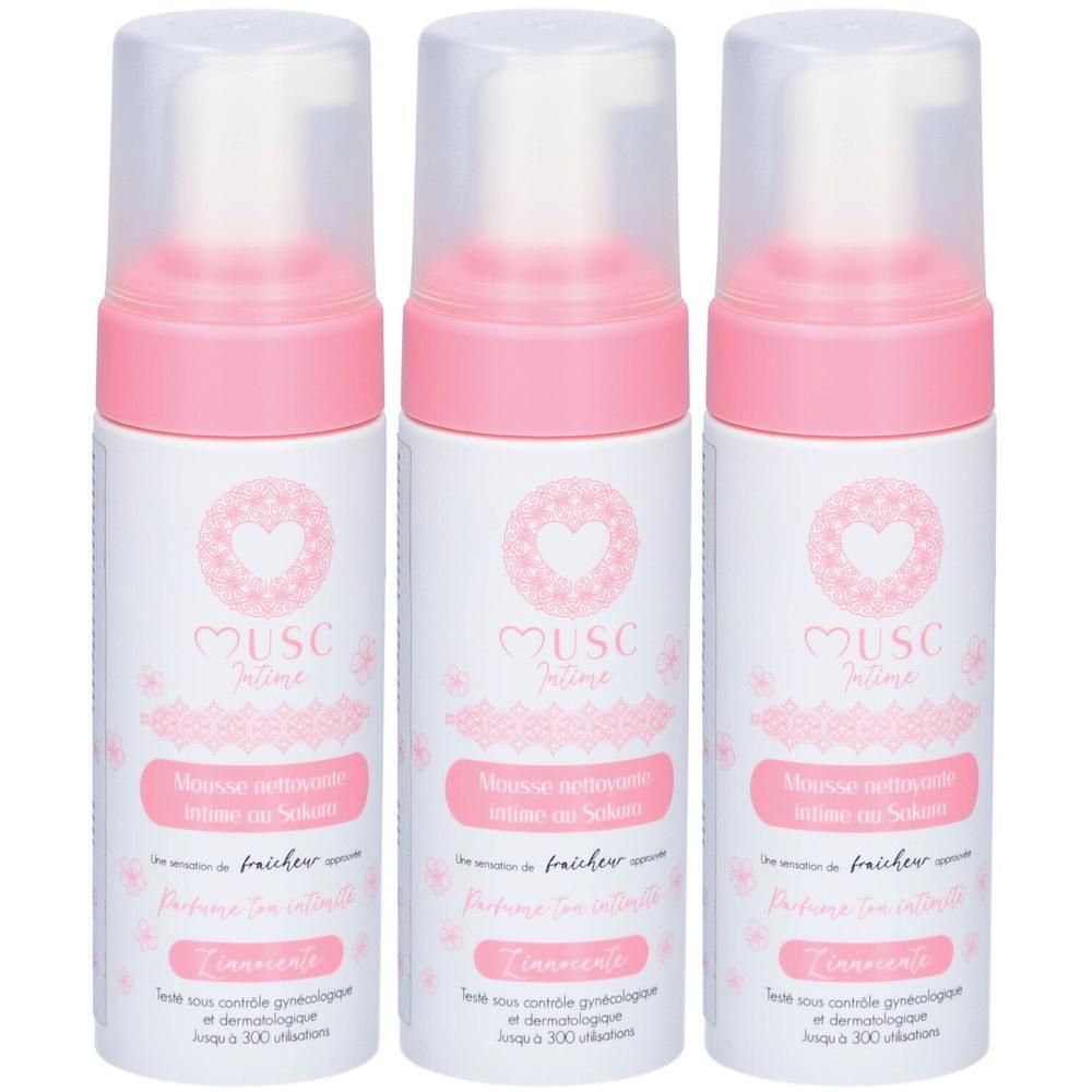 Trois flacons de mousse nettoyante intime, design rose et blanc, motifs cœur et fleurs.