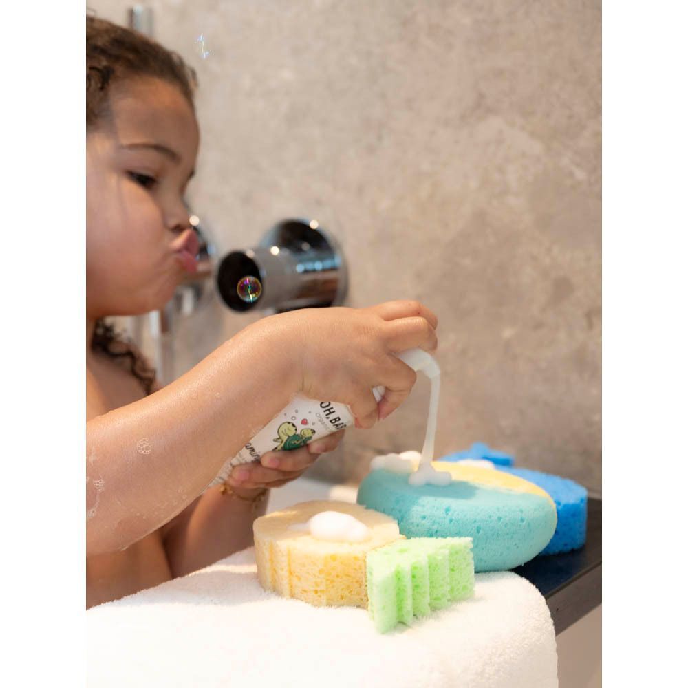 Enfant utilisant la mousse lavante Oh Baby! dans la salle de bain avec différentes éponges.