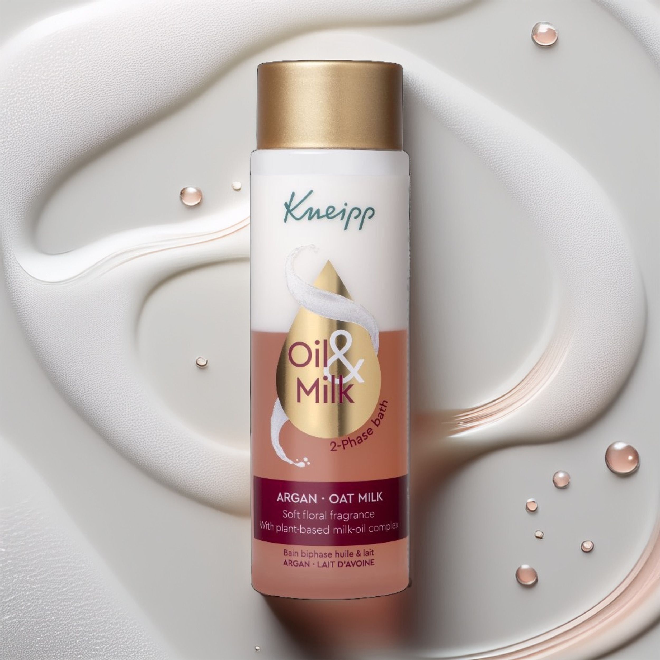 Une bouteille d'huile de bain biphasée Kneipp Argan & Lait d'avoine sur une surface crémeuse et fluide.