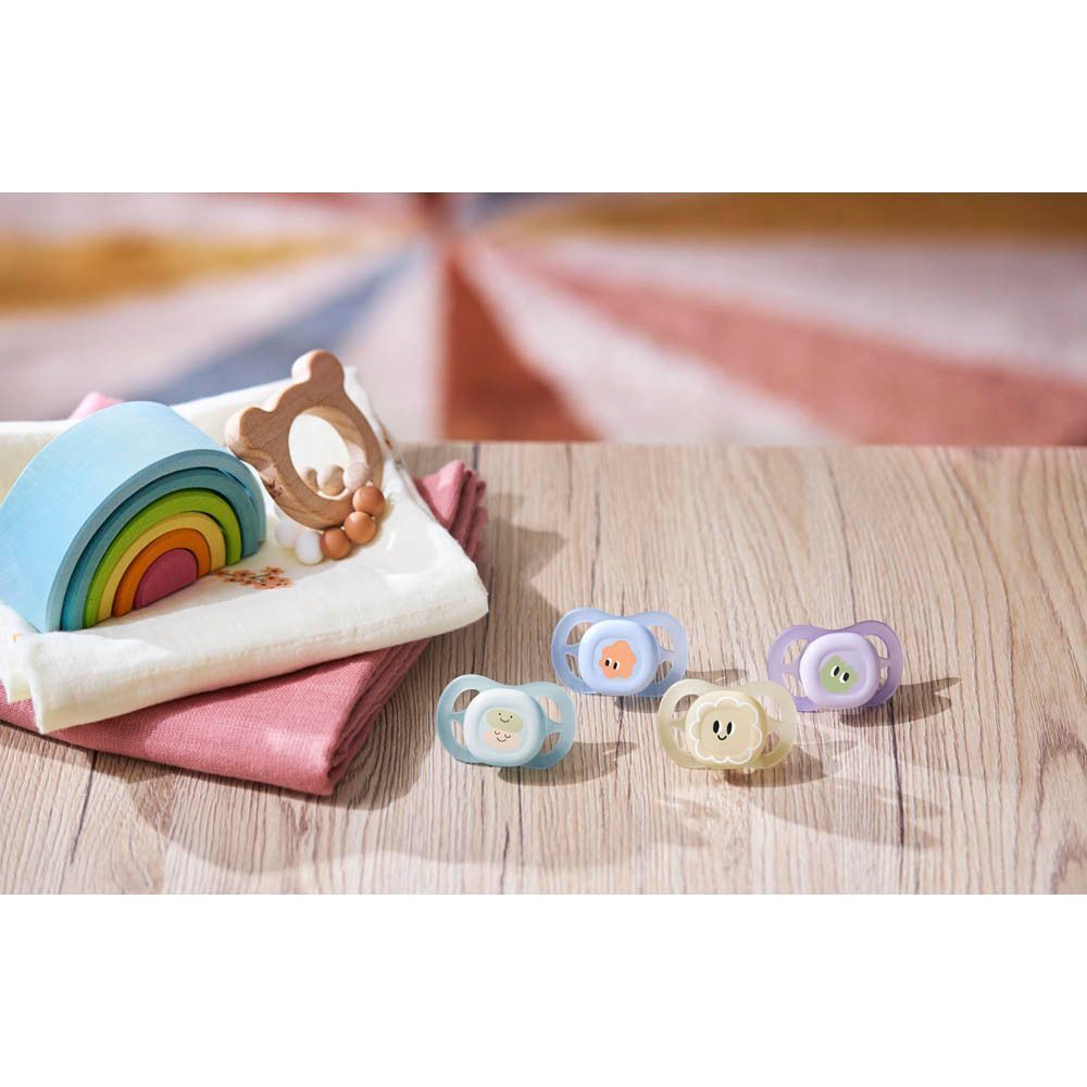 Cinq sucettes colorées sur une table en bois avec des jouets.