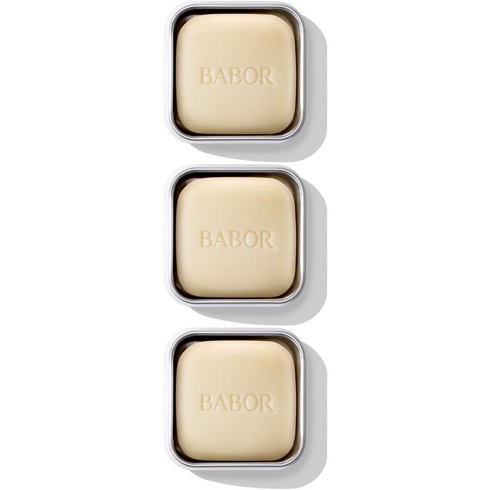 Trois pains de savon Babor dans des boîtiers argentés, empilés les uns sur les autres. Chaque savon est gravé du logo Babor.