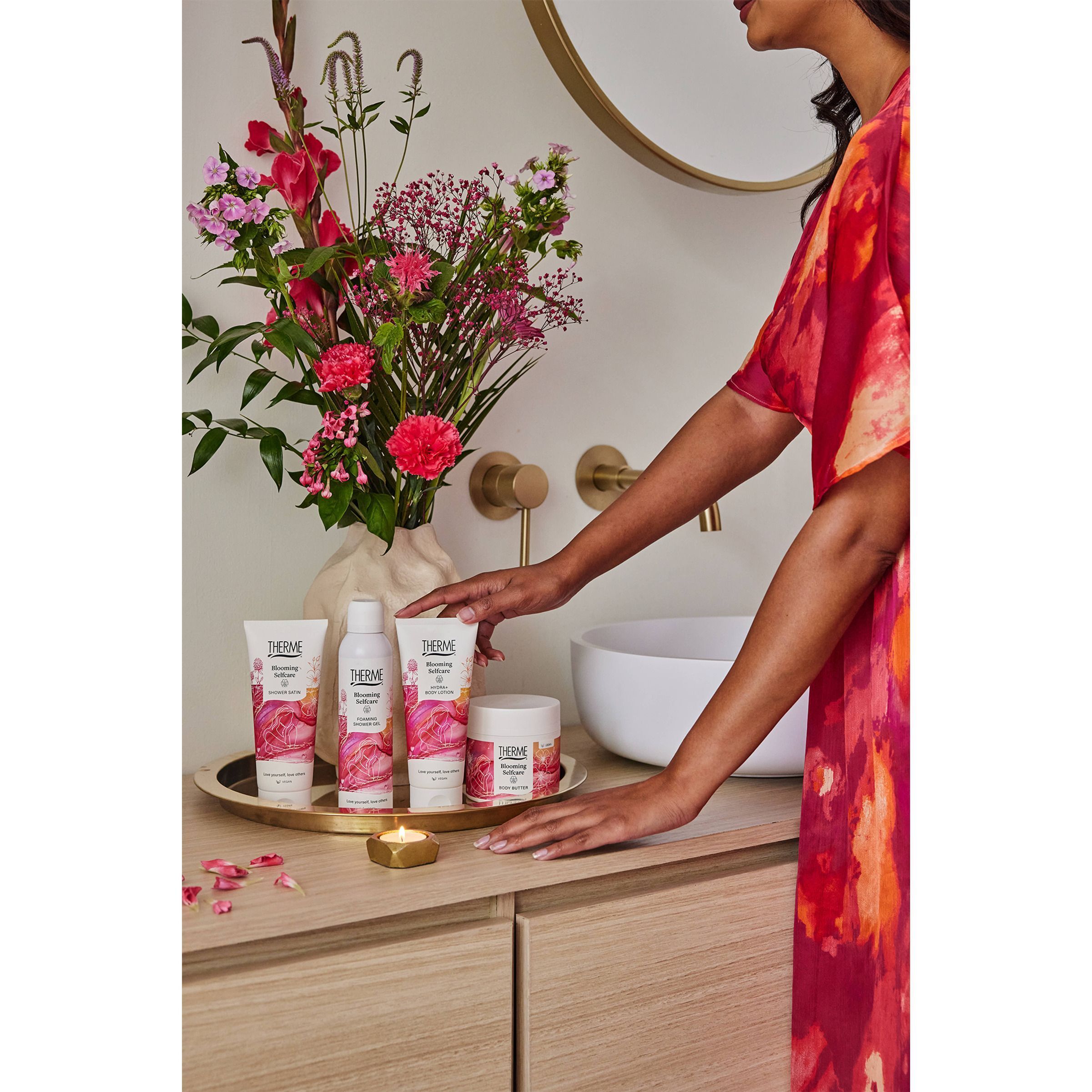 Een vrouw raakt een selectie Therme Blooming Selfcare producten aan op een dienblad.