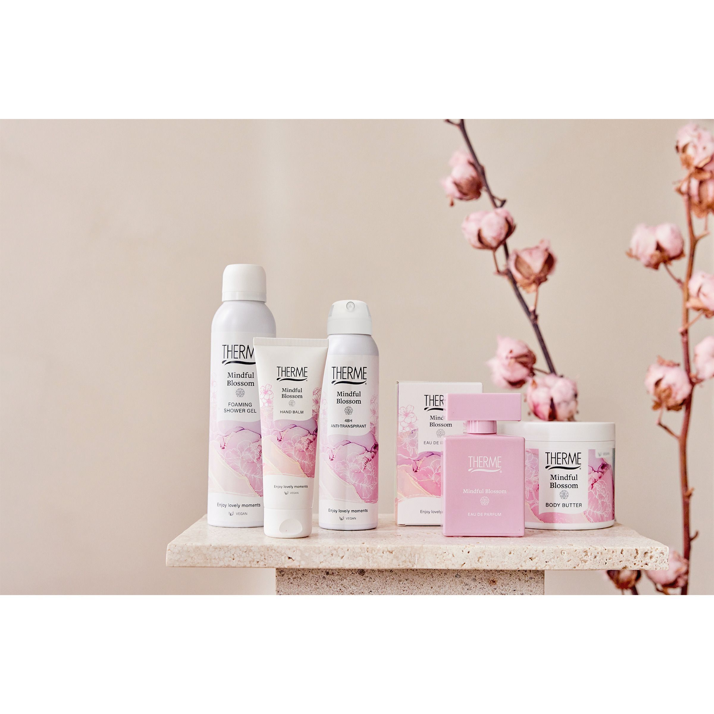 Therme Mindful Blossom producten op een tafel, met katoenbloesems en roze bloemen.