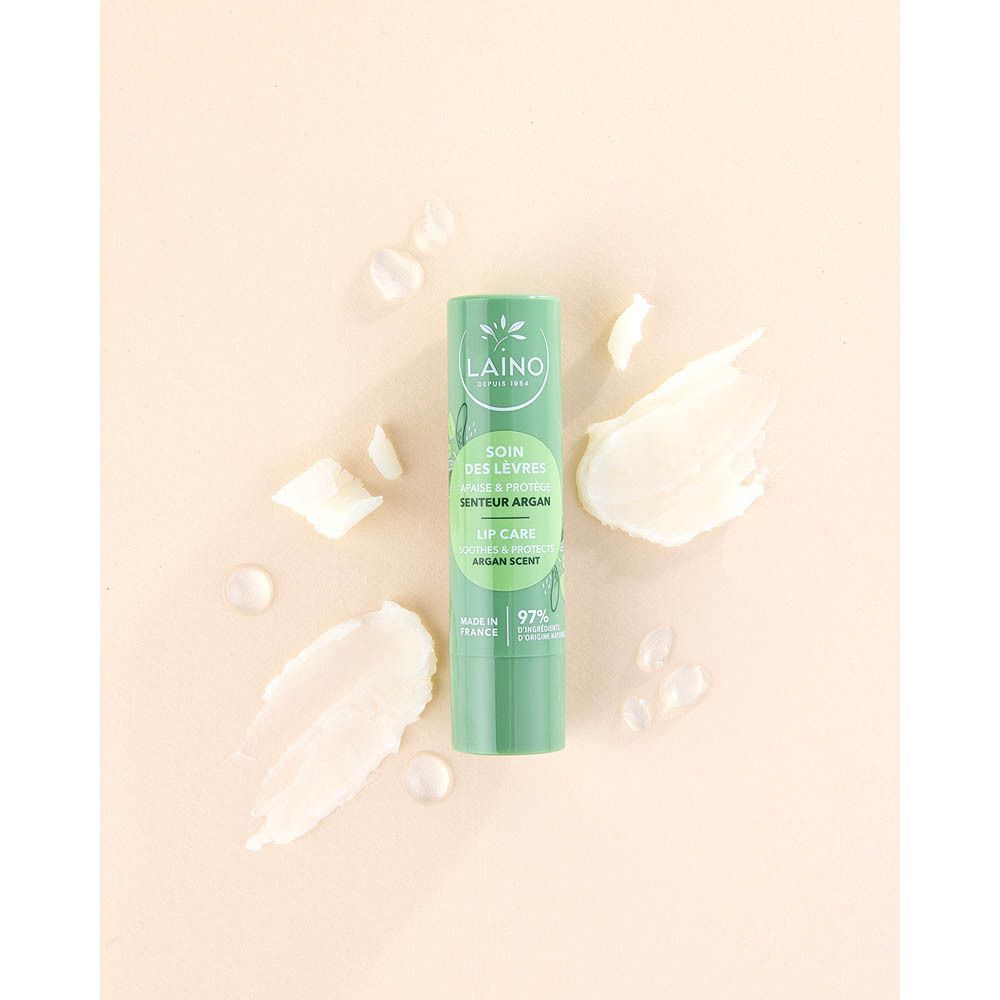 Een groene lippenbalsemstick met argangeur, omringd door crèmige vegen en druppels.