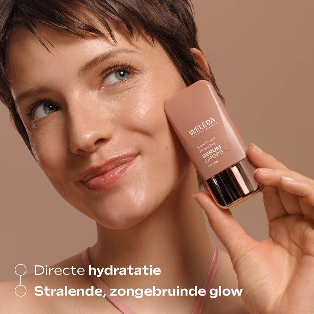 Vrouw houdt Weleda Sunkissed Bronzing Serum Drops flesje bij de wang.