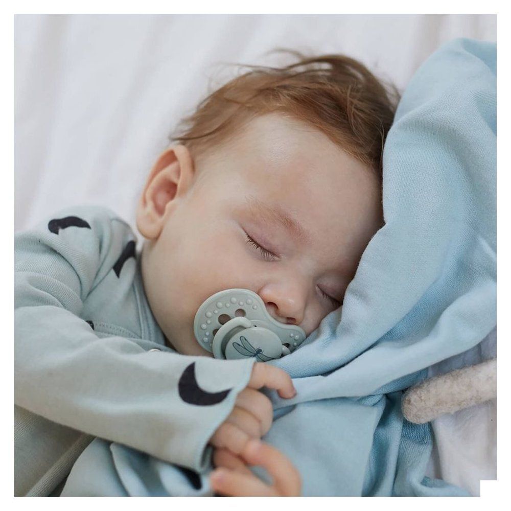 Bébé endormi avec une sucette vert clair.