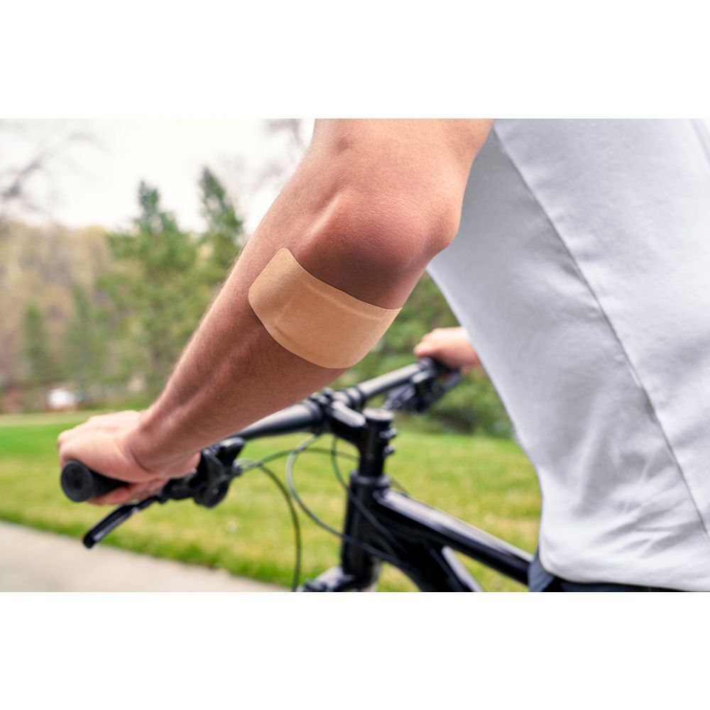 Homme à vélo avec un pansement Nexcare Ultra Stretch Maxi sur le coude.
