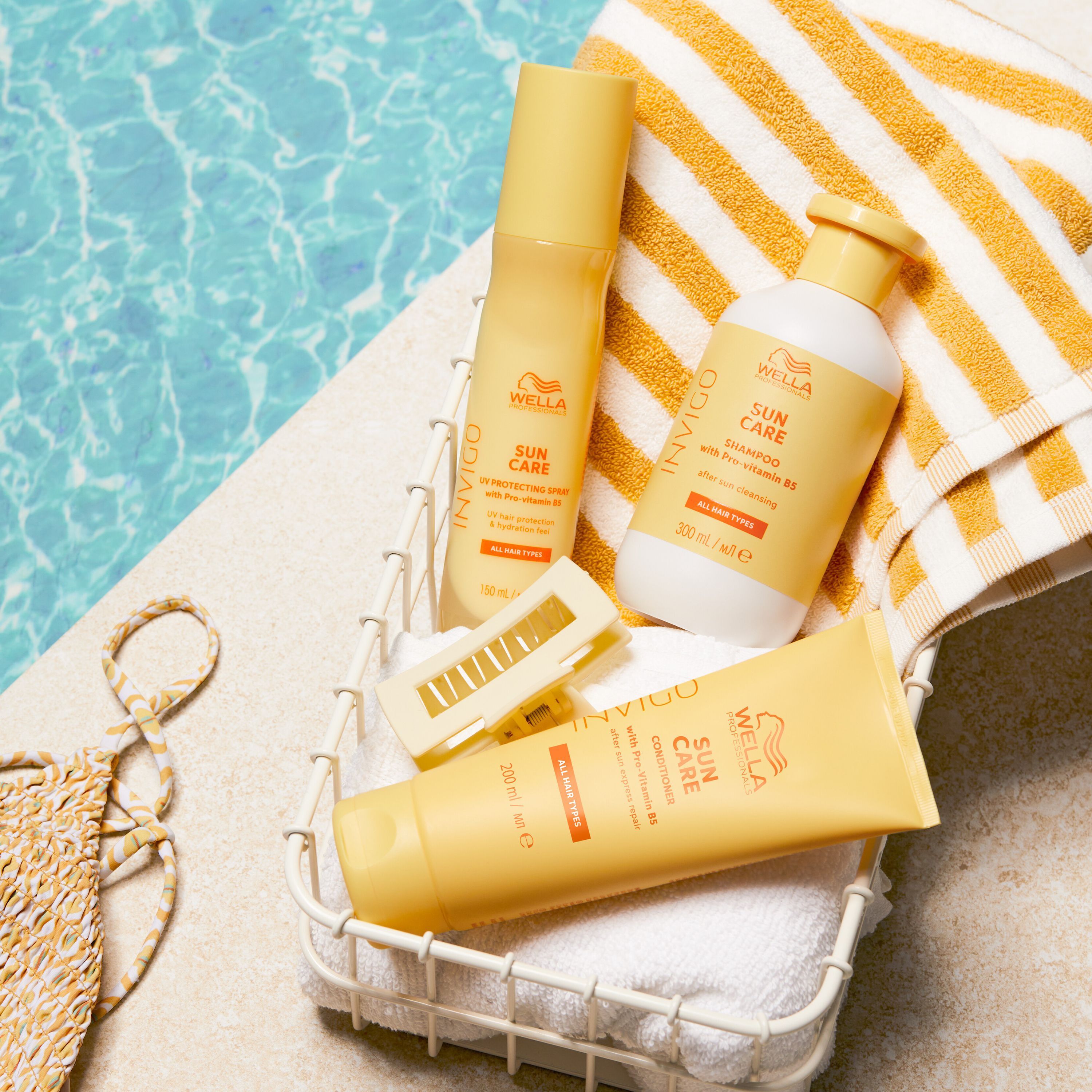 Produits Wella Invigo Sun Care dans un panier au bord de la piscine : shampoing, spray après-soleil, soin capillaire.
