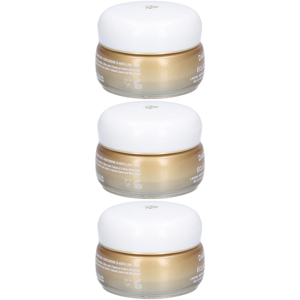 Trois pots de crème dorés avec couvercles blancs, empilés.