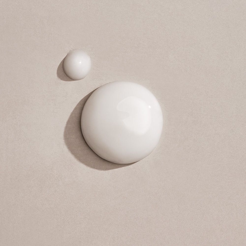 Deux gouttes de texture de sérum blanc sur fond clair.