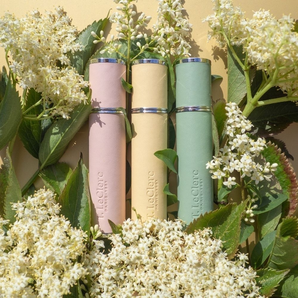 Trois vaporisateurs de parfum T. LeClerc roses, jaunes et verts avec capuchons argentés.