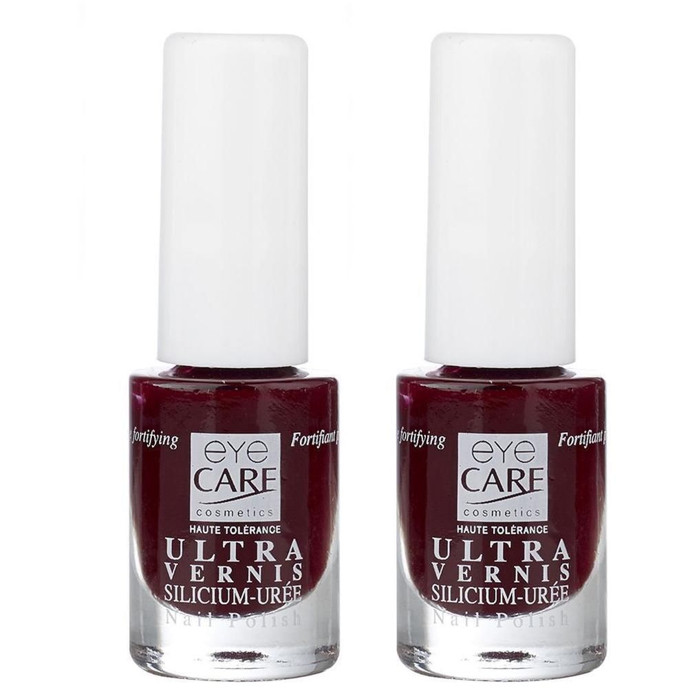 Twee flacons Eye Care Ultra Vernis nagellak in donkerrood. Heldere glazen flesjes met witte doppen.
