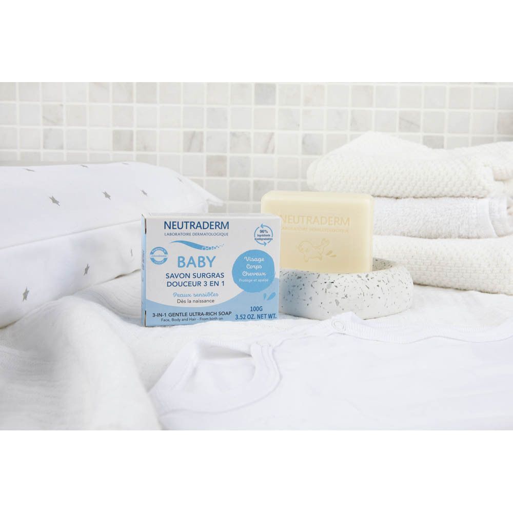 Emballage et pain de savon Neutroderm Baby Savon Surgras Douceur 3-en-1 à côté de vêtements de bébé.