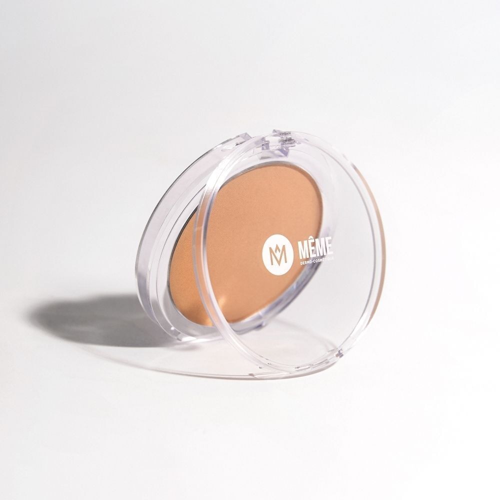 Poudre bronzante dans un boîtier rond avec couvercle transparent ouvert, posé sur le côté.