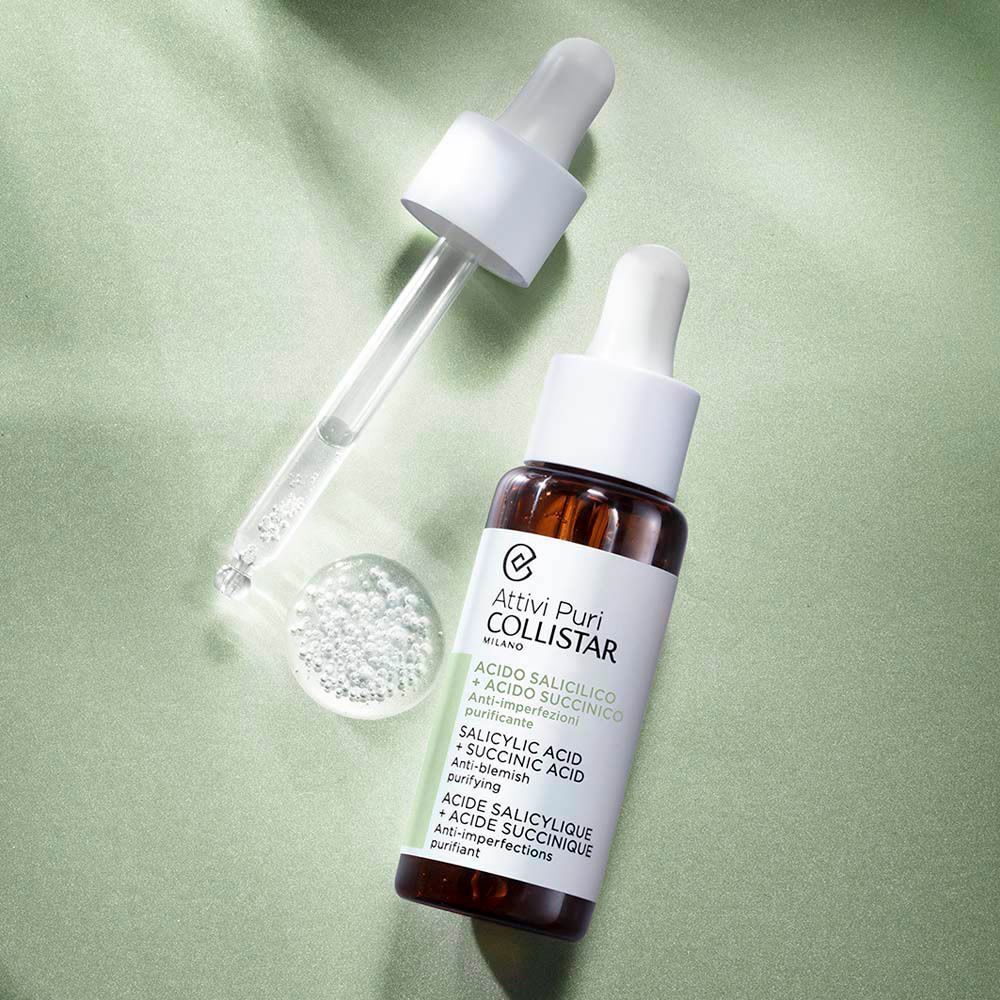 Flacon Collistar Attivi Puri avec pipette et gouttes de sérum. Petite bouteille en verre brun sur fond vert.