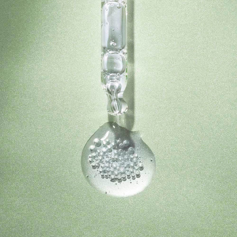 Pipette avec gouttes de sérum et bulles. Liquide clair avec des bulles d'air.