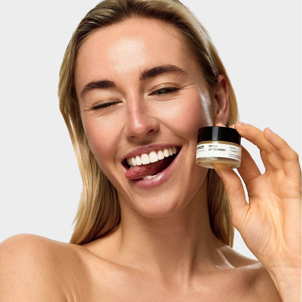 Une femme tient un petit pot de baume à lèvres 'The Remedy Peptide Lip Treatment'.