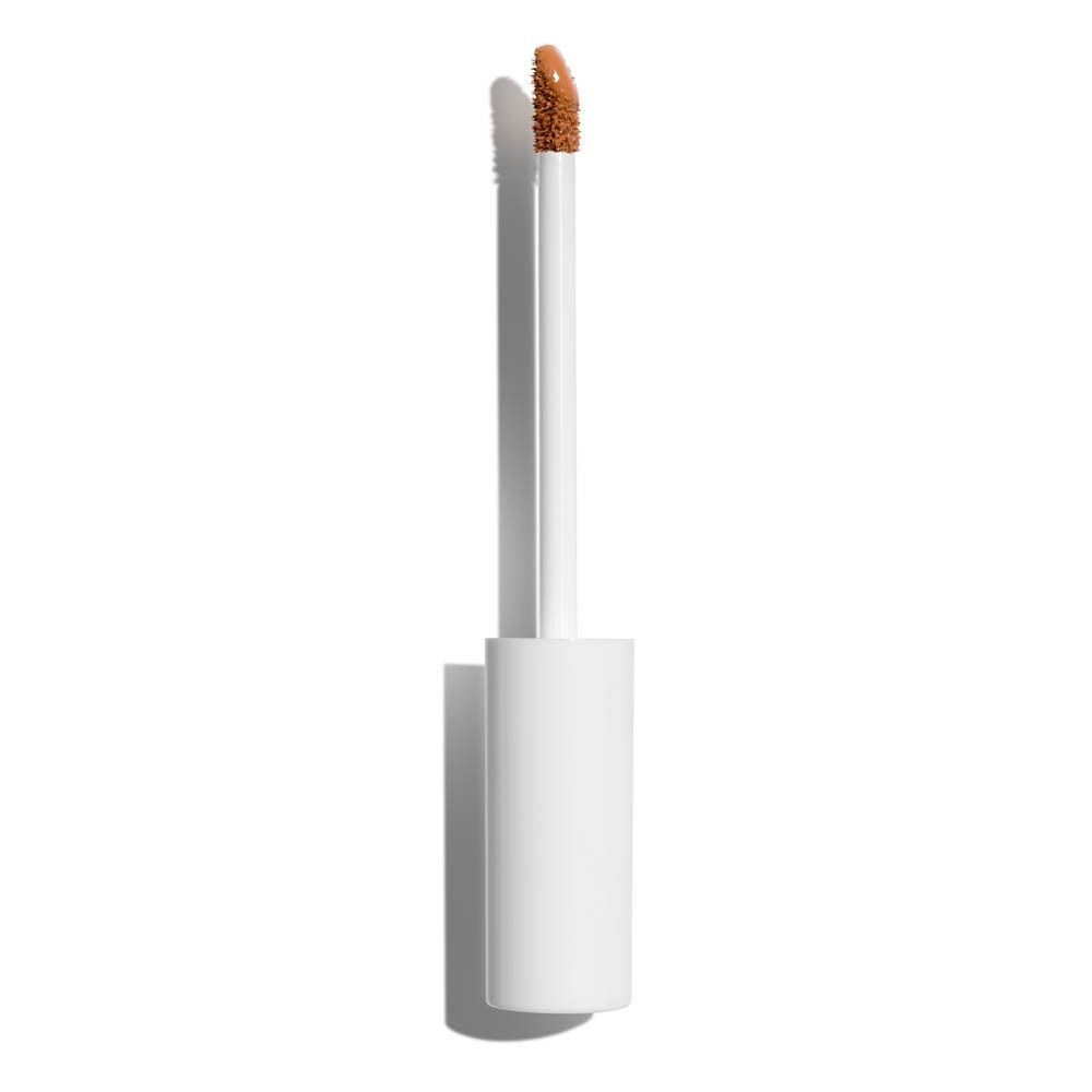 Een witte applicator met bruine vloeibare concealer.
