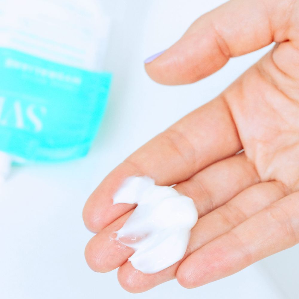 Une main avec une crème blanche appliquée sur la paume à partir d'un sachet SVR Hydraliane.