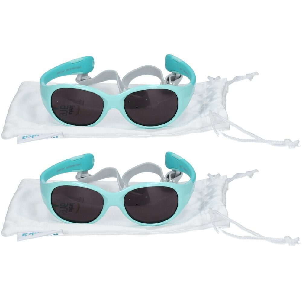 Twee turquoise kinderzonnebrillen met donkere glazen en verstelbare bandjes, elk in een wit zakje.