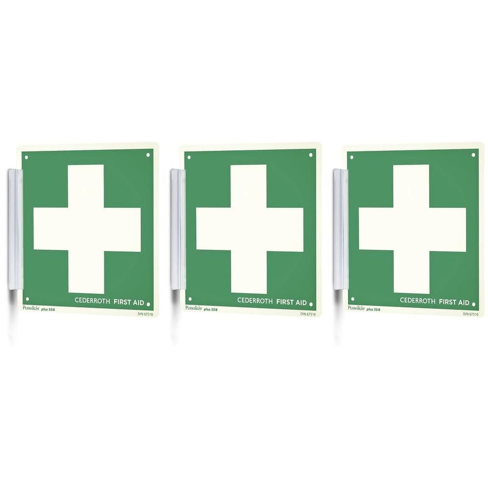 Trois panneaux verts avec croix blanche et inscription "CEDERROTH FIRST AID", fixés sur des supports muraux.
