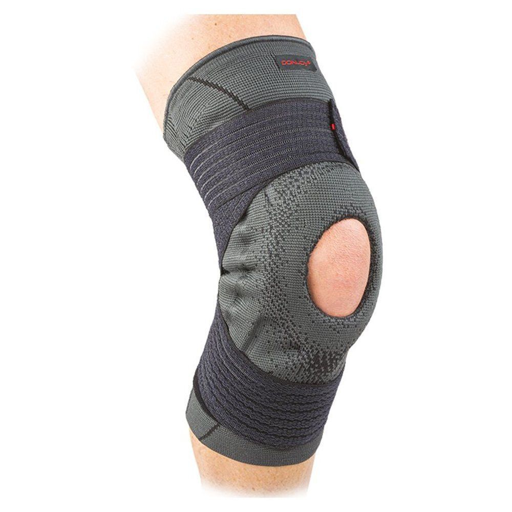 Genouillère grise avec découpe rotulienne, portée sur le genou, avec zones de compression.
