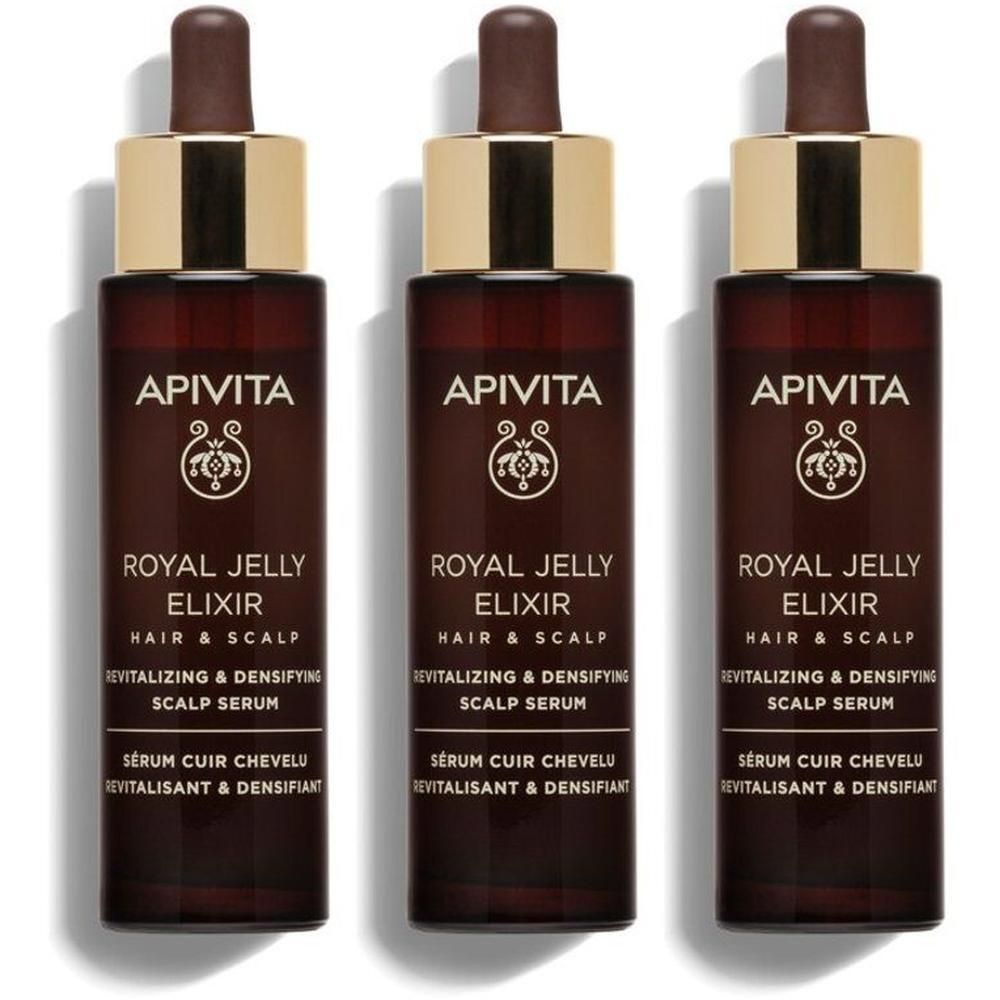 Trois flacons de sérum Apivita Royal Jelly Elixir Cheveux & Cuir Chevelu avec pipettes. Flacons en verre brun foncé avec un collier doré.