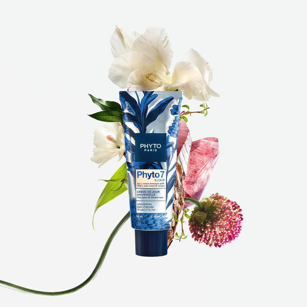 Un tube de Phyto 7 Elixir Crème de jour universelle entouré de fleurs et de cristaux.